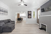 A modern living room with a dark gray sectional sofa, light wood floors, a fireplace, and an arched doorway leading to a kitchen.